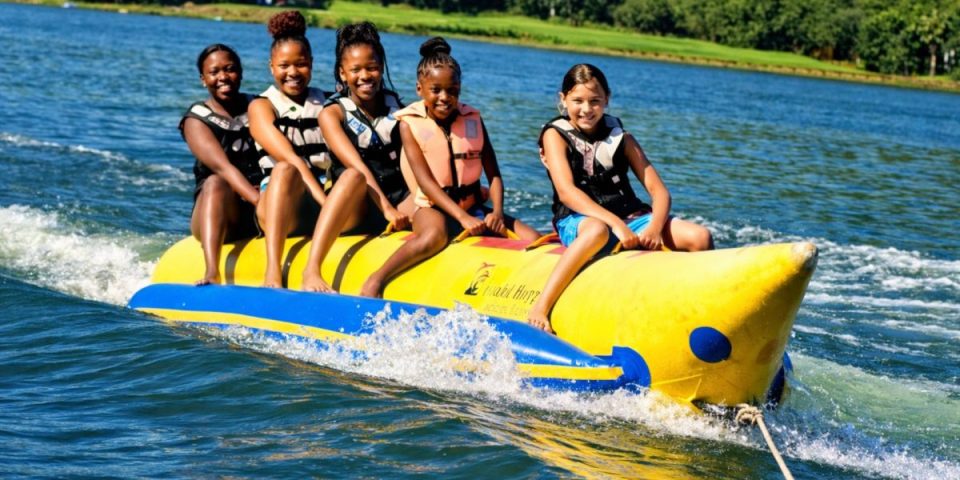 Group of friends enjoying a wake snake ride on Waterworld lake, holding on as the inflatable speeds across the water.